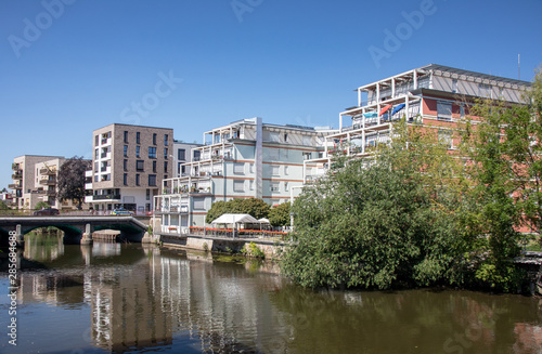 Modern residential buildings in Leipzig scene district Schleussig directly on the river Elster with bridge with blue sky and sunshine