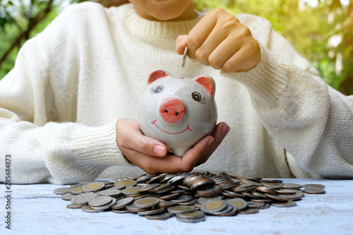 Scattered coins in the wooden backgroundpiggy bank, Hands of business, Concept of saving money for future. photo