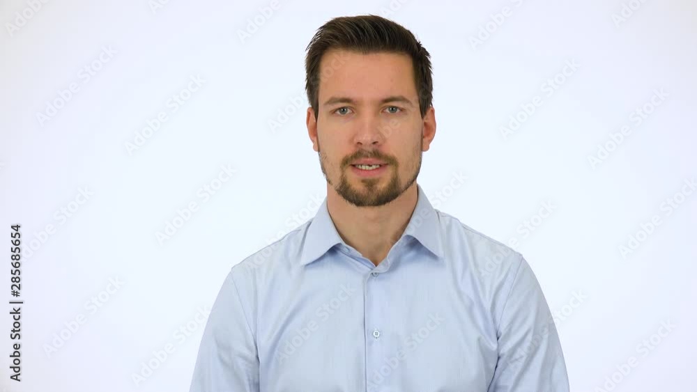 A young handsome man talks seriously to the camera - white screen studio A young handsome man talks seriously to the camera - white screen studio