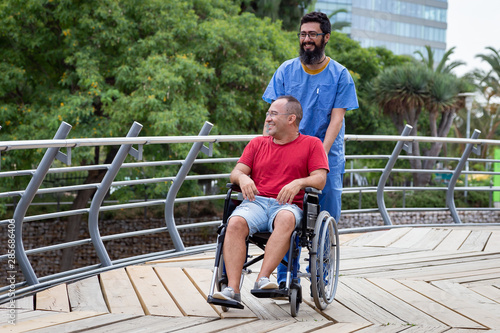 disabled man in wheelchair walking with his caretaker