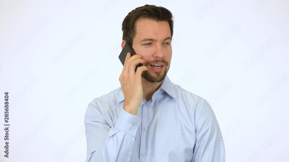 A young handsome man talks on a smartphone with a smile - white screen studio A young handsome man talks on a smartphone with a smile - white screen studio