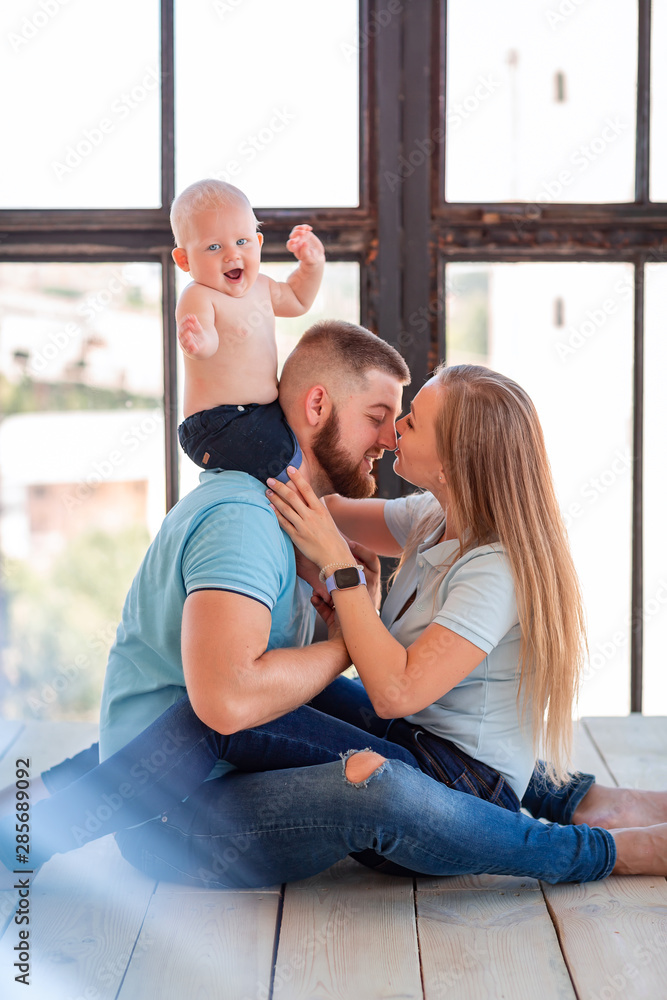 Young happy family with the baby indoors - obrazy, fototapety, plakaty 