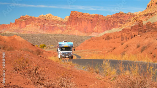 RV Camper traveling past mesa and butte mountain formations in red rock desert © helivideo