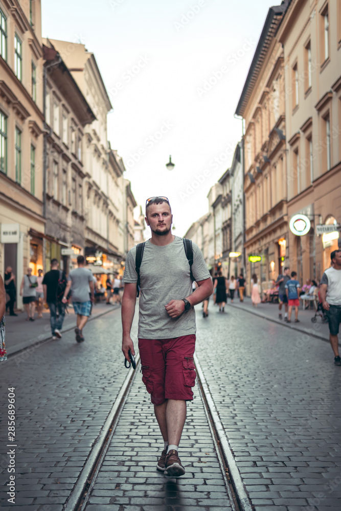 portrait of a walking man on the streets of the evening city. Restaurant in the background, historical center. Krakow Poland, vertical photo