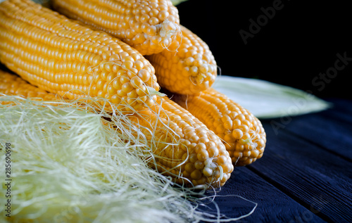 Fresh juicy yellow corn bonduel with green leaves lies on the wooden table photo