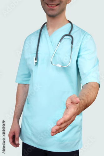 male doctor in blue uniform professional clothes with a stethoscope on his neck holds out his hand for greeting on a white background, medical concept, close-up, copy space