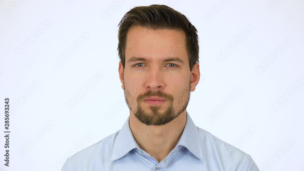 A young handsome man looks seriously at the camera - closeup - white screen studio A young handsome man looks seriously at the camera - closeup - white screen studio