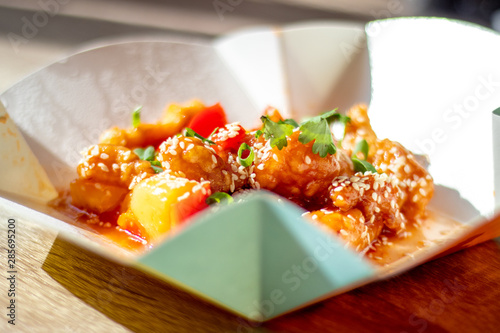 Chinese spicy chicken with food delivery in sweet and sour sauce with pineapple and bell pepper sprinkled with onions