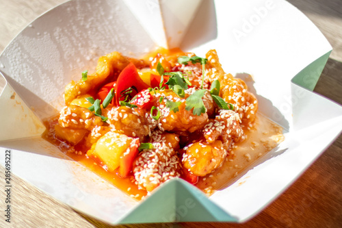 Chinese spicy chicken with food delivery in sweet and sour sauce with pineapple and bell pepper sprinkled with onions