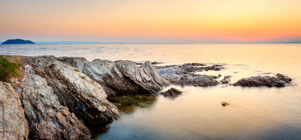 Panoramic view of narrow reef on Paradisos beach in Neos Marmaras and Turtle island during golden hour