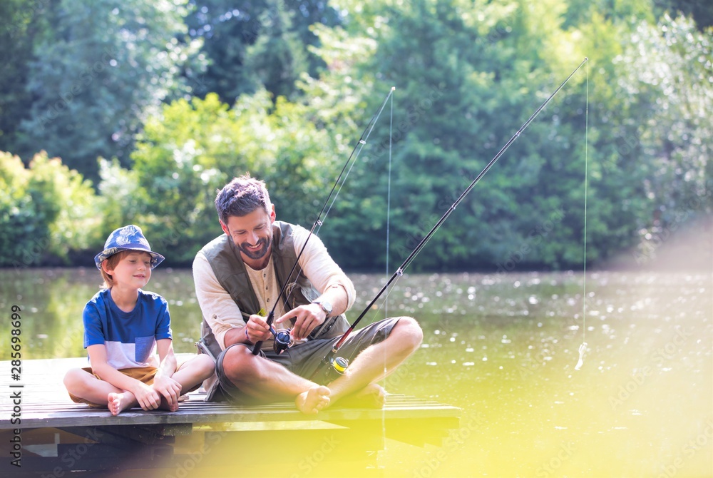 Father and son fishing in Lake while sitting on pier