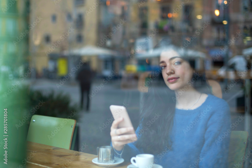 Young businesswoman in a cafe- seen through window Young businesswoman in a cafe- seen through window