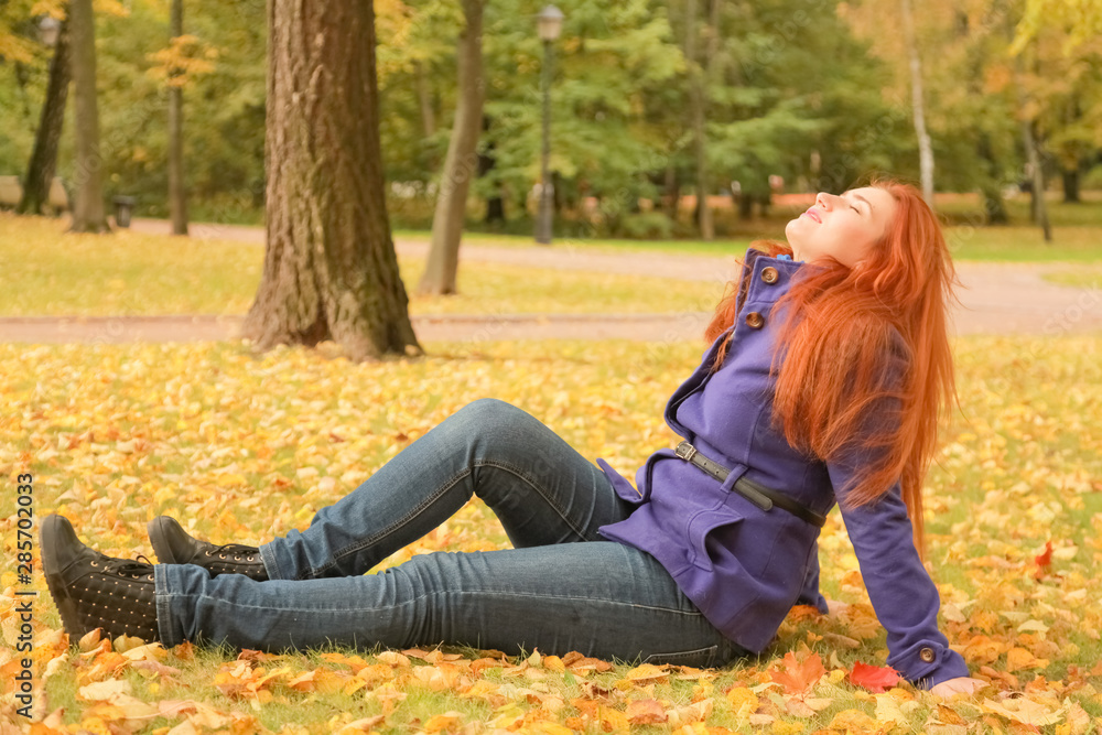 young pretty caucasian woman with red hair wearing purple jacket and walks in autumn park young pretty caucasian woman with red hair wearing purple jacket and walks in autumn park