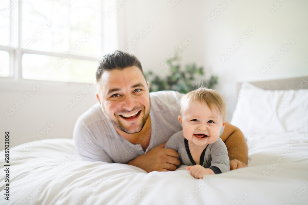 A Father with cute baby son on bed at home A Father with cute baby son on bed at home