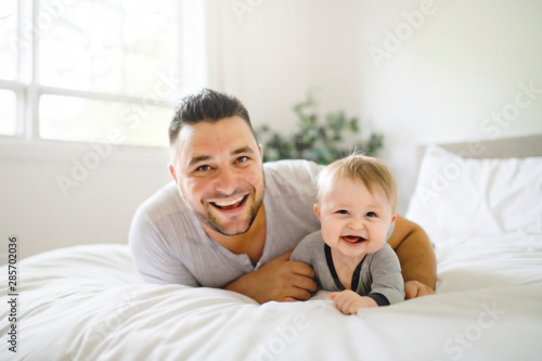 A Father with cute baby son on bed at home © Louis-Photo
