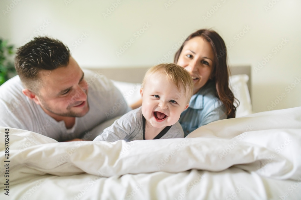 happy family mother, father and son at home in bed