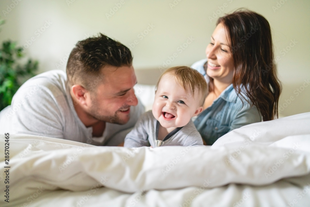 happy family mother, father and son at home in bed