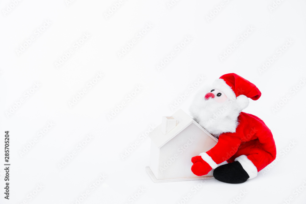 Santa claus doll holding a small wooden house on isolated on white background,Christmas decoration Santa claus doll holding a small wooden house on isolated on white background,Christmas decoration