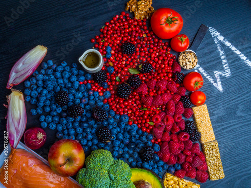 Healthy eating and heart health concept with a heart shaped with blueberries, raspberries, blackberries, cranberries, broccoli, onion, olive oil, salmon, beans, seeds, nuts, full of vitamins and antio photo