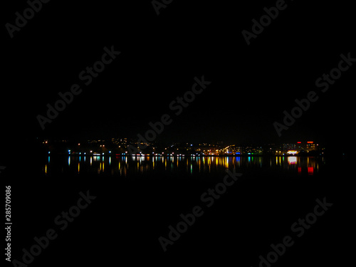 Wonderful night city landscape. Night city lights reflected in the water. The nightlife of the city in its remote manifestations.