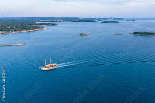 Pleasure boat sailing on the sea. In the background you can see the coastline of the Green lagoon. Poreс, Croatia. The view from the top. Copy space. © ROMAN DZIUBALO