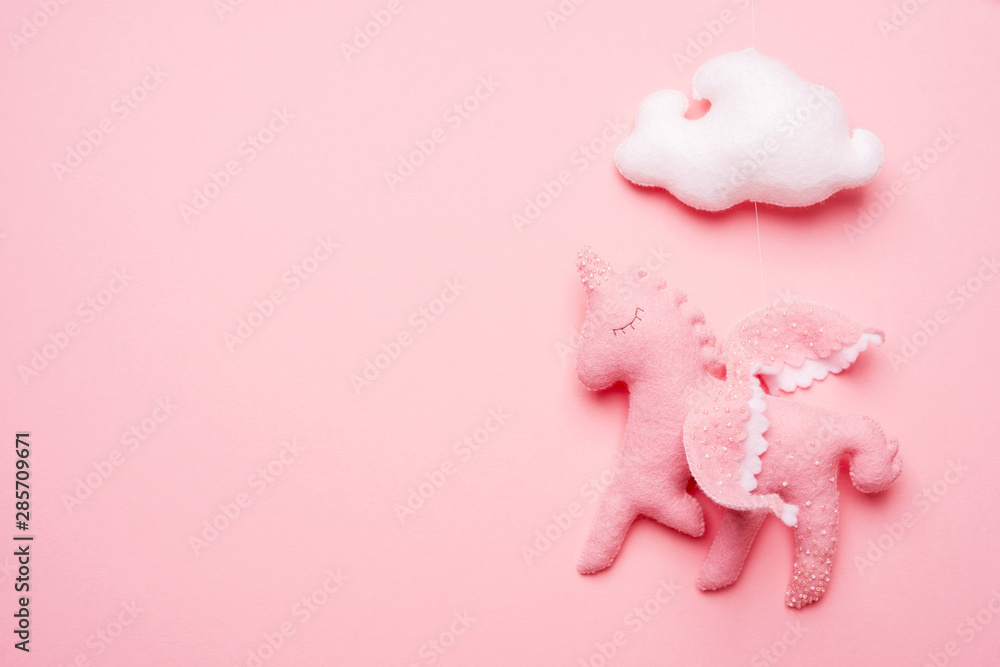 Close-up of felt toy unicorn from baby mobile on pink background with copy space. Preparation for the birth of a child. Baby shower. - obrazy, fototapety, plakaty 