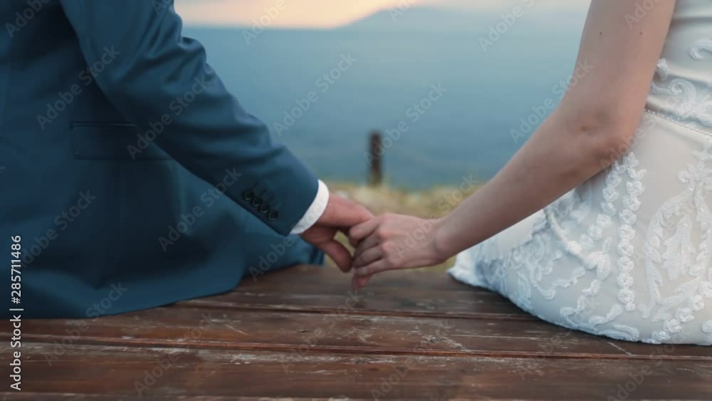 Close up newlyweds hold hands and swing on swing, wedding day Close up newlyweds hold hands and swing on swing, wedding day