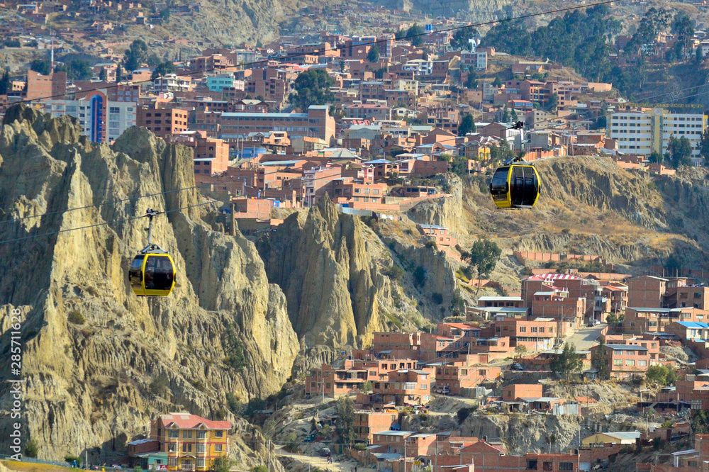 Two yellow cable cars crossing the city of La Paz, Bolivia