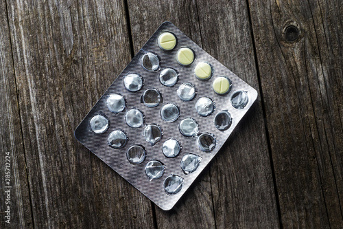 half empty pack of pills on wooden background