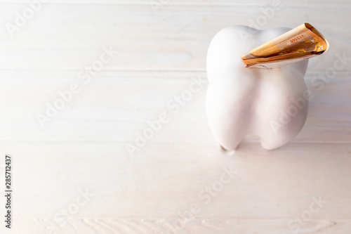 big tooth in the form of a piggy bank. it has the euro. paid dentistry.