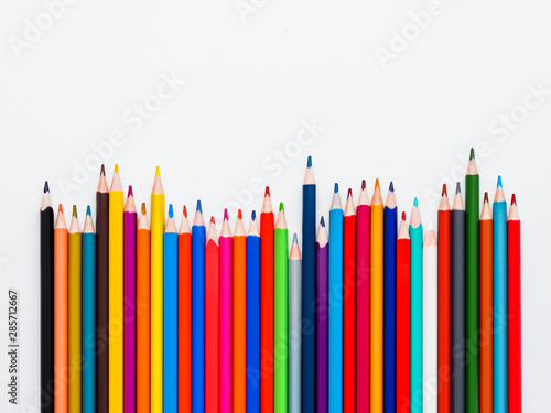 Row of colorful watercolor pencils on white background. School supplies on light paper background. Kid's stationery with copy space. Back to school backdrop.