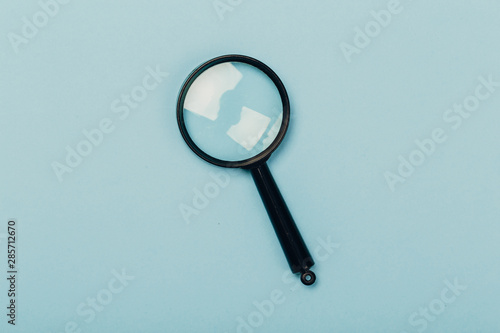 Small magnifying glass on pastel blue background