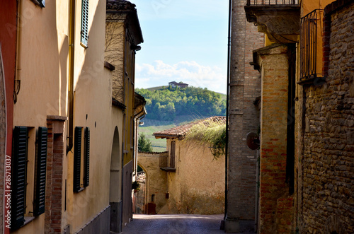 Narrow street and facades with house on a hill in the background, in Piamonte, Italy photo