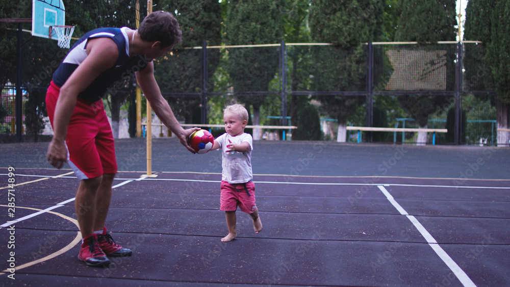 Obraz premium Athletic father and his little son playing on basketball playground.