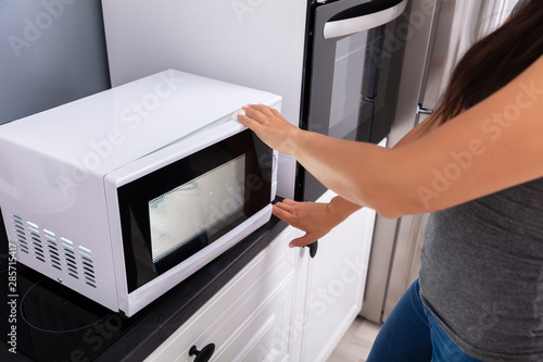 Woman Pressing Button Of Microwave Oven