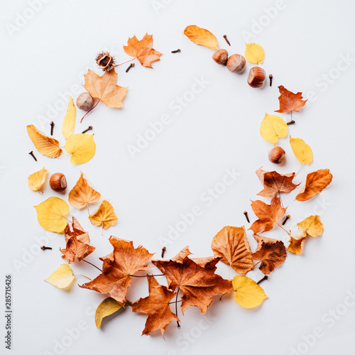 Autumn floral design greeting card. Fall yellow leaves wreath on white surface. Thanksgiving day, seasonal concept. Copy space.