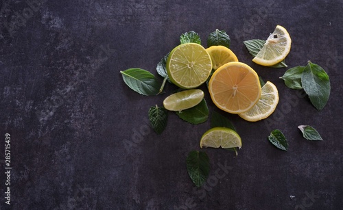 Slices of lemon and lime with mint leaves on dark background