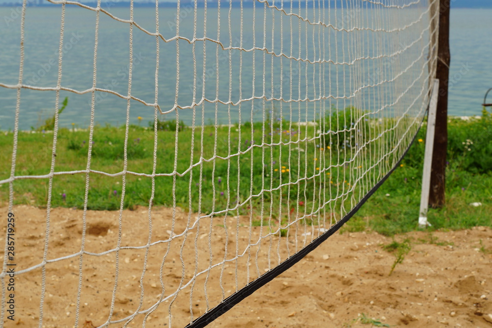 Part of the volleyball net is located in a meadow near the lake.