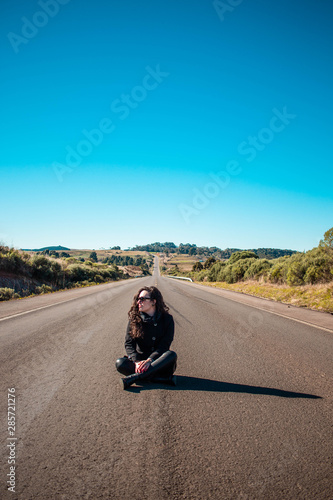 Modelo sentanda no meio de uma estrada deserta