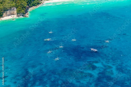 Aerial view from the drone on the landscape tropical sand beach with palm trees and turquoise sea with boats. Summer vacation concept.