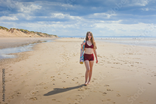 pretty young woman on the beach with a yoga mat © Jolyon Rogers