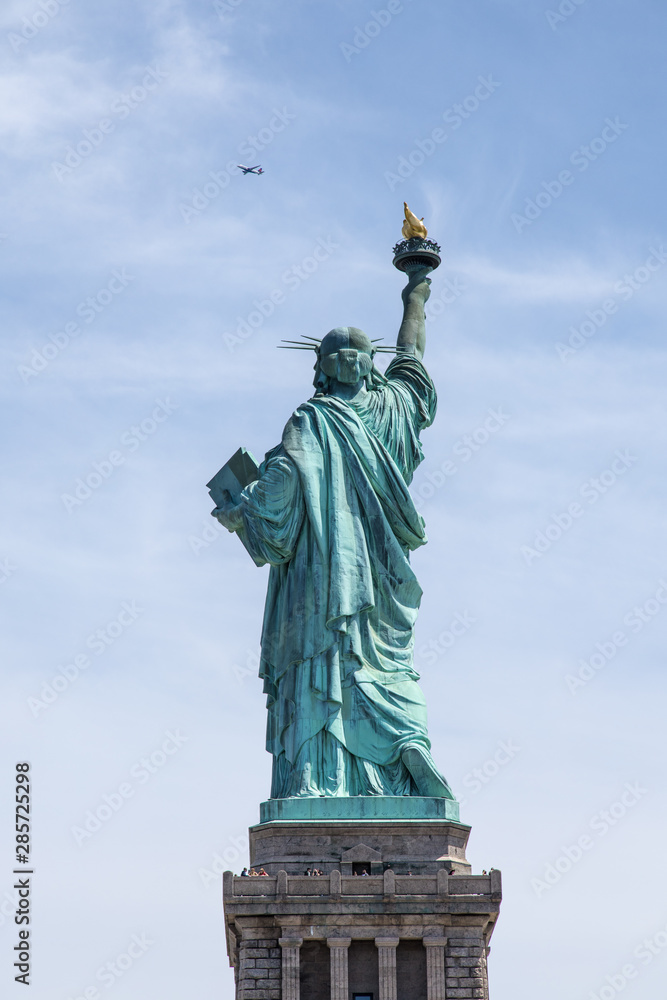 Fototapeta premium Statue of Liberty back and airplane in New York