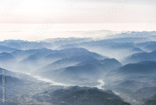 Landscape aerial view of colorful blue Alps mountains with clouds, rivers, and fog above Switzerland