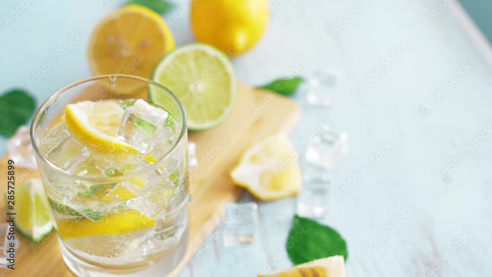 Close up slow motion of ice falling intro glass with slice lime and lemon. Fresh coctail stay on chopping board. Summer drink. Close up slow motion of ice falling intro glass with slice lime and lemon. Fresh coctail stay on chopping board. Summer drink.