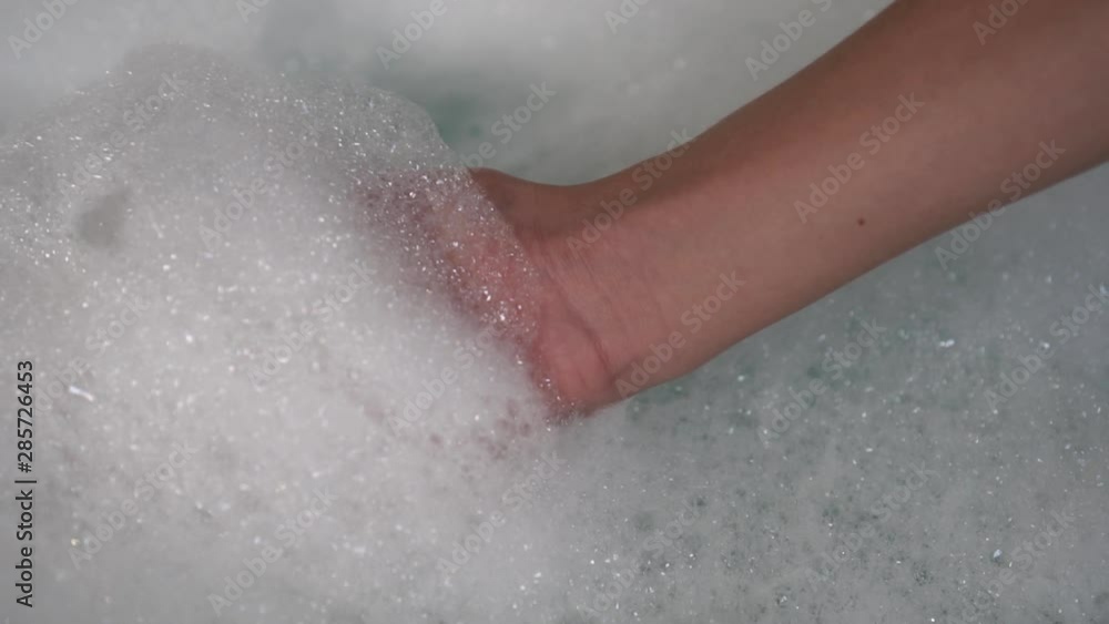 A teenager picks up a bunch of fresh foam from a bathtub. Bubbles burst A teenager picks up a bunch of fresh foam from a bathtub. Bubbles burst