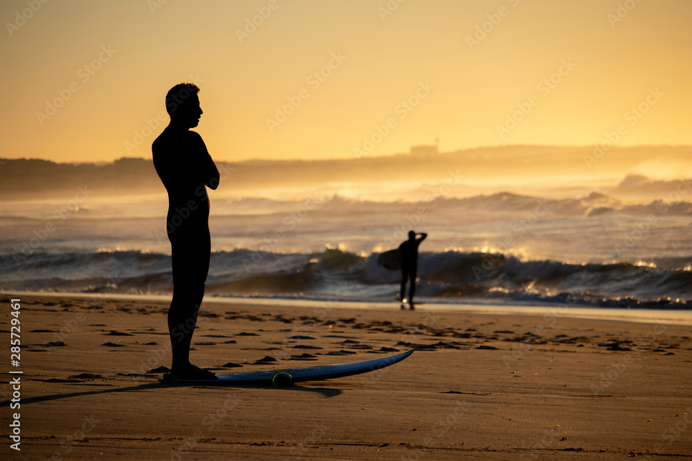 A surfer is stretching and getting ready to surf the waves at a beach
