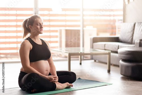 Pregnancy & Yoga. Young pregnant woman doing yoga. Copy space on the right side
