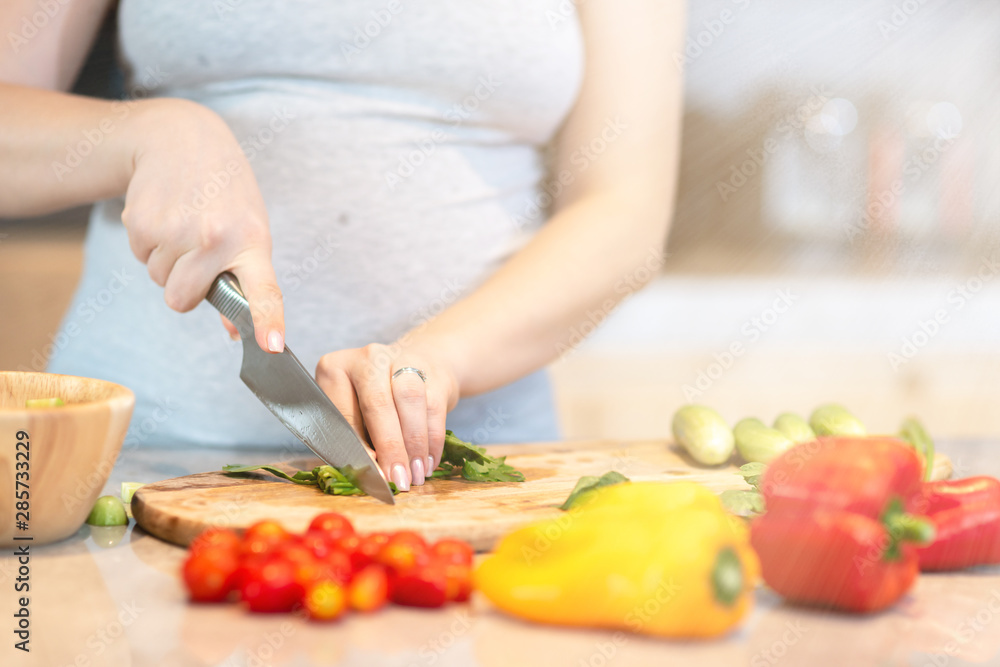 Eat smart. Young pregnant woman is preparing a salad. Copy space in upper right part