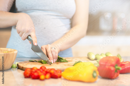 Eat smart. Young pregnant woman is preparing a salad. Copy space in upper right part
