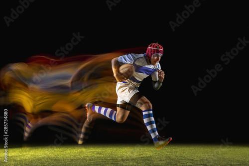 Caught in important moment. One caucasian man playing rugby on the stadium in mixed light. Fit young male player in motion or action during sport game. Concept of movement, sport, healthy lifestyle. © master1305